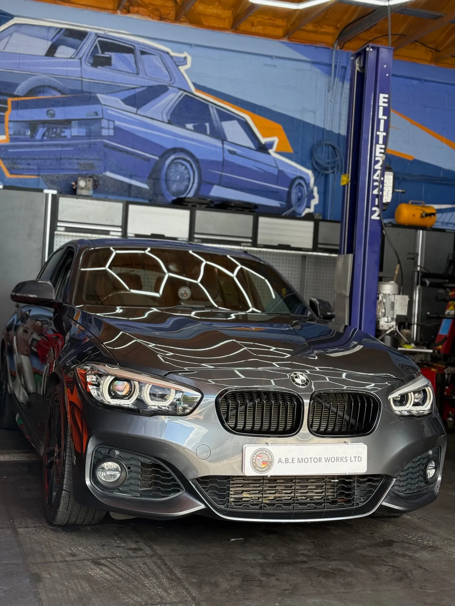 A car parked in a garage with a painting on the wall.