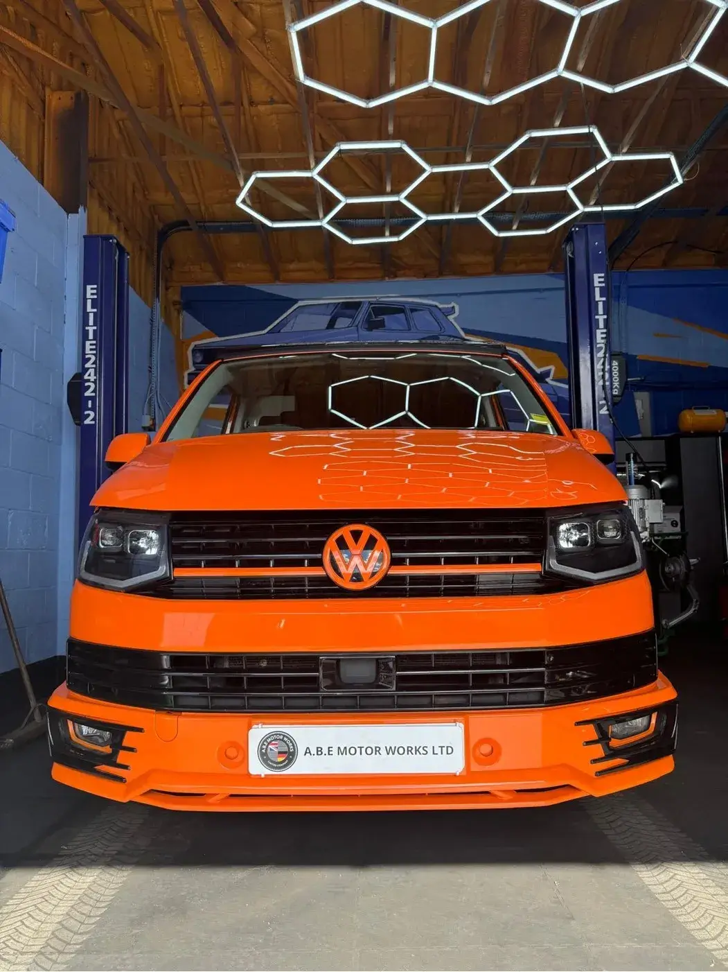 a close up of a orange volkswagen van parked in a garage