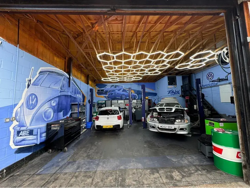 there are two cars parked in a garage with a mural on the wall